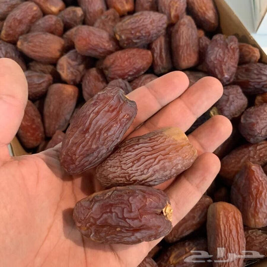 Hand full of Premium Medjool Dates with their fresh, wrinkled texture can be seen